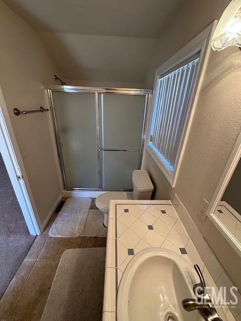 bathroom featuring tile patterned floors, toilet, walk in shower, and sink