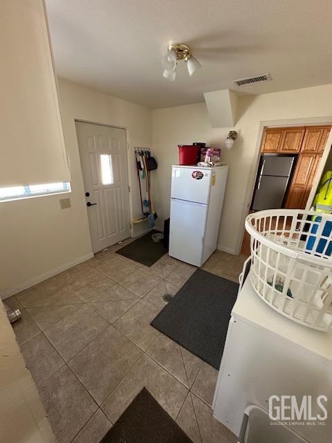 interior space featuring stainless steel refrigerator, white fridge, and light tile patterned flooring