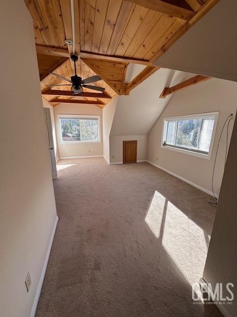 additional living space featuring dark colored carpet, vaulted ceiling with beams, ceiling fan, and wooden ceiling