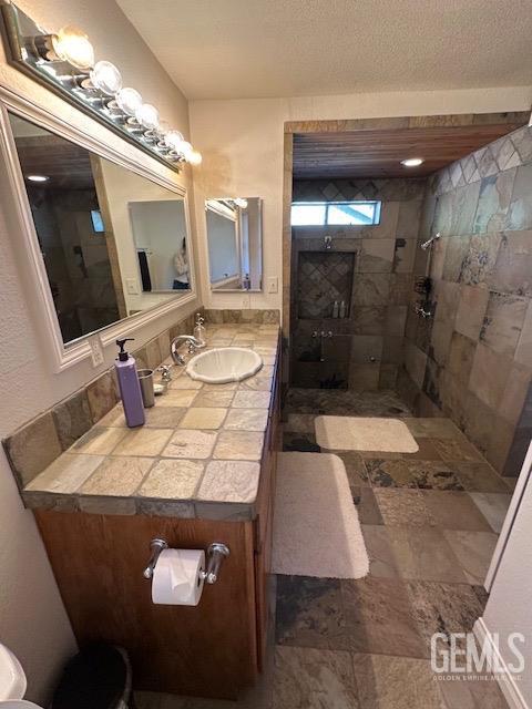 bathroom with a tile shower and vanity