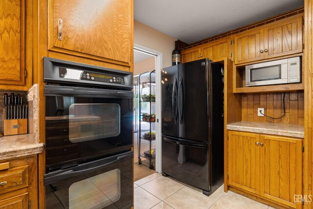 2924 Elm St, Bakersfield, CA 93301 - kitchen with black appliances, brown cabinets, light countertops, and light tile patterned floors
