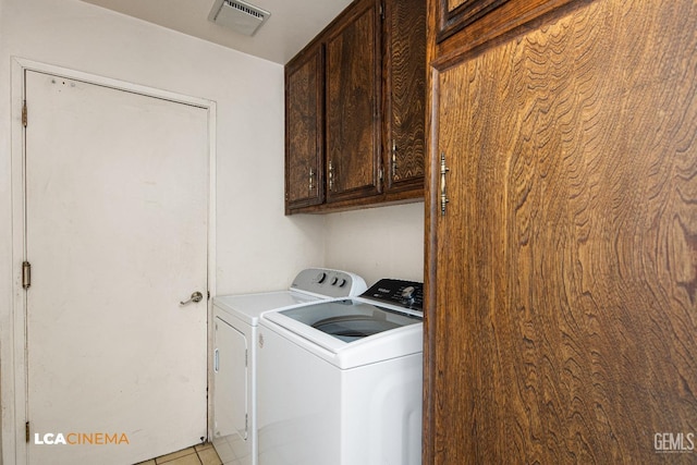 laundry room featuring washer and clothes dryer, visible vents, cabinet space, and light tile patterned flooring