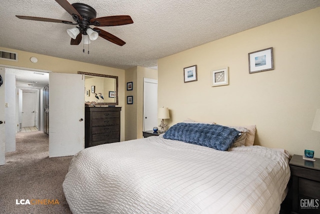 carpeted bedroom with visible vents, a textured ceiling, and a ceiling fan