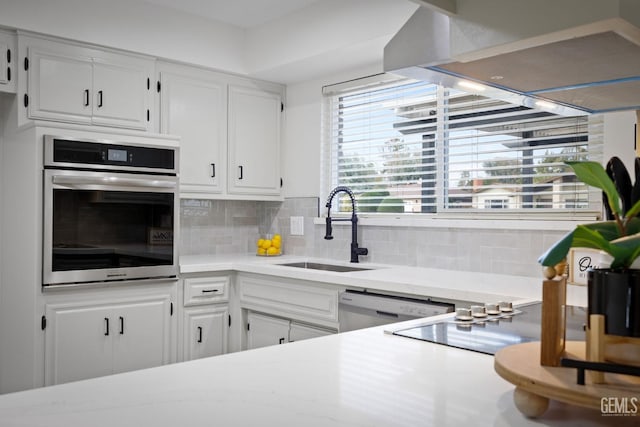 kitchen featuring light countertops, appliances with stainless steel finishes, white cabinetry, a sink, and extractor fan