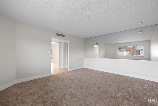 unfurnished room featuring baseboards, visible vents, a textured ceiling, and light colored carpet