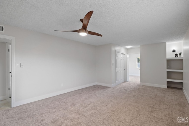 empty room featuring visible vents, baseboards, a textured ceiling, and light colored carpet