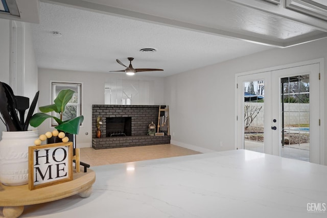 living area with a textured ceiling, a wealth of natural light, a brick fireplace, and visible vents