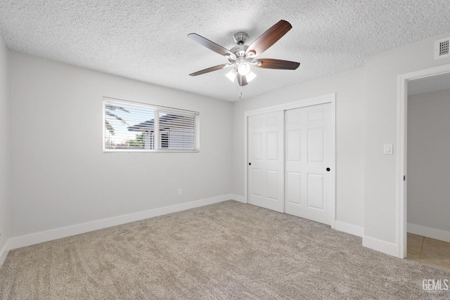 unfurnished bedroom featuring carpet floors, a textured ceiling, baseboards, and a closet