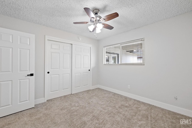 unfurnished bedroom with a closet, light carpet, a textured ceiling, and baseboards