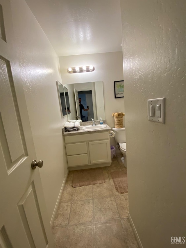 half bathroom featuring toilet, vanity, and baseboards