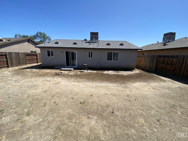 rear view of property featuring central AC, a fenced backyard, and stucco siding