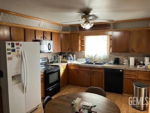 kitchen with black appliances, ceiling fan, light hardwood / wood-style floors, and sink