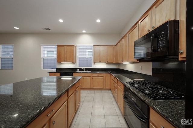 kitchen with dark stone countertops, sink, light tile patterned floors, and black appliances