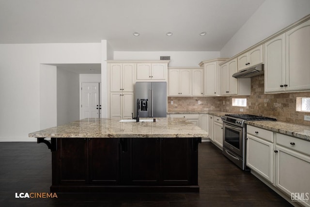 kitchen with stainless steel appliances, a kitchen island, light stone counters, and decorative backsplash