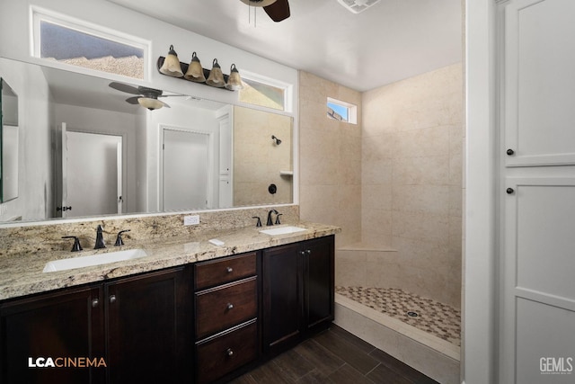 bathroom featuring vanity, wood-type flooring, ceiling fan, and tiled shower