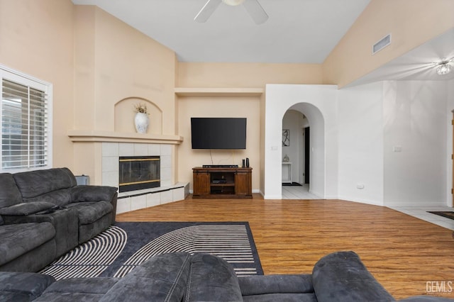 11011 Southwales Ct, Bakersfield, CA 93312 - living area featuring a tile fireplace, wood finished floors, visible vents, arched walkways, and ceiling fan