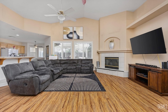 11011 Southwales Ct, Bakersfield, CA 93312 - living area with high vaulted ceiling, a tiled fireplace, light wood-style floors, and a ceiling fan