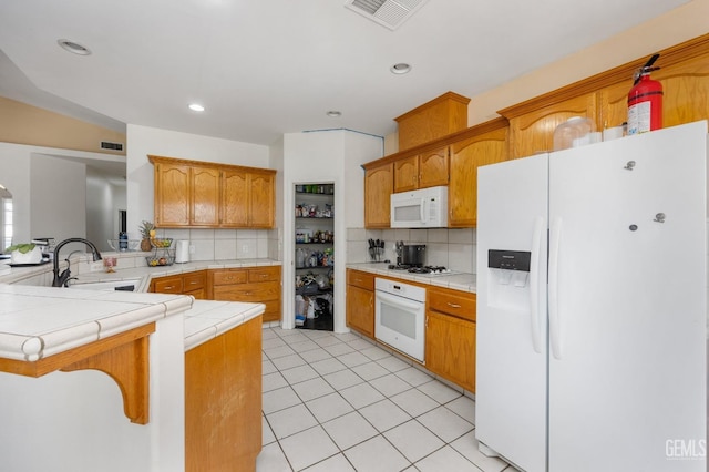 11011 Southwales Ct, Bakersfield, CA 93312 - kitchen with visible vents, tile counters, a peninsula, white appliances, and a sink