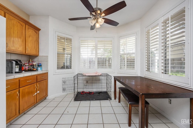 11011 Southwales Ct, Bakersfield, CA 93312 - kitchen featuring light tile patterned floors, backsplash, tile countertops, a ceiling fan, and brown cabinets