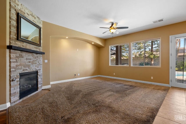 unfurnished living room featuring baseboards, visible vents, a ceiling fan, tile patterned flooring, and a fireplace