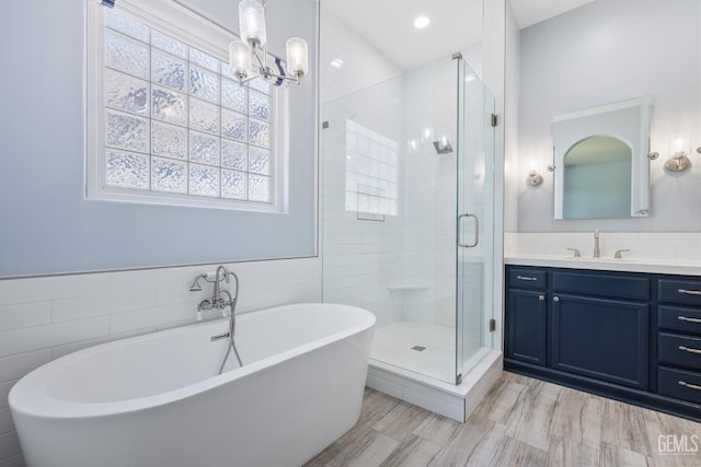 full bath with tile walls, a wealth of natural light, vanity, and a stall shower