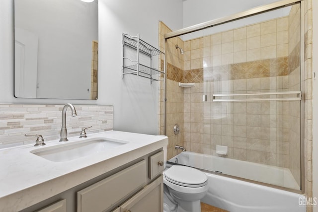bathroom featuring toilet, vanity, enclosed tub / shower combo, and tasteful backsplash