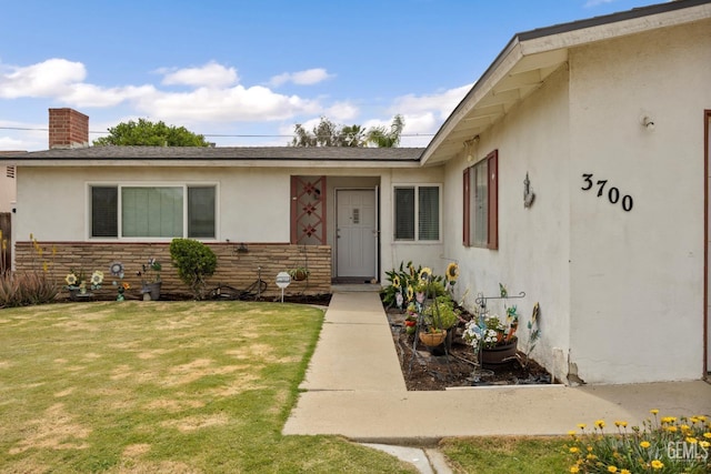 3700 Wenatchee Ave, Bakersfield, CA 93306 - view of exterior entry featuring a yard, a chimney, stucco siding, and a shingled roof