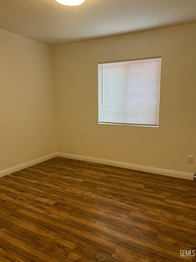 spare room with dark wood-style floors and baseboards