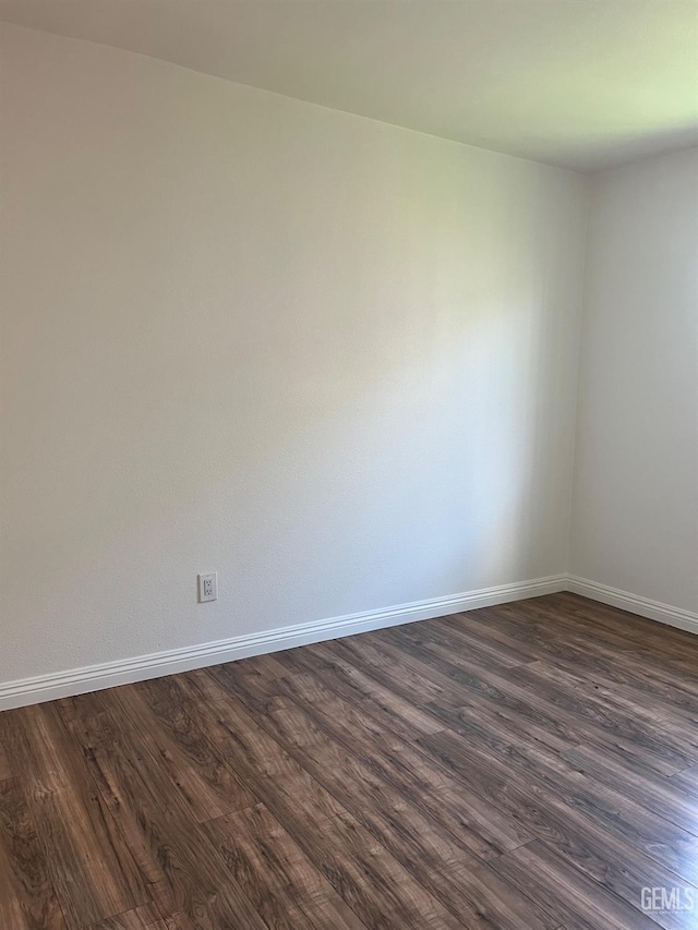 unfurnished room with dark wood-style floors and baseboards