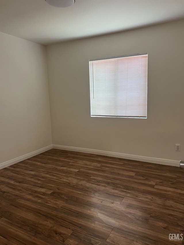 empty room with dark wood-style flooring and baseboards