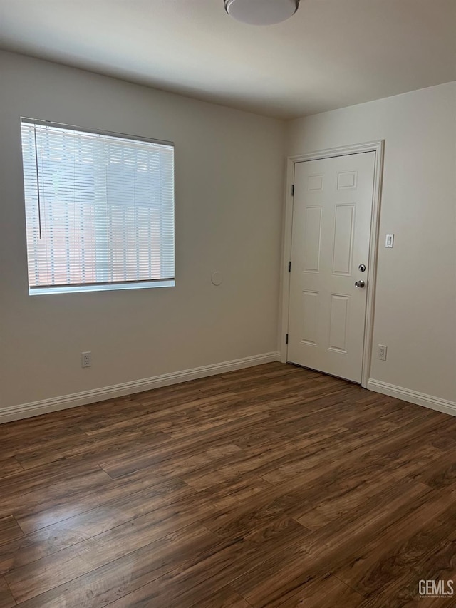 empty room with dark wood-style flooring and baseboards