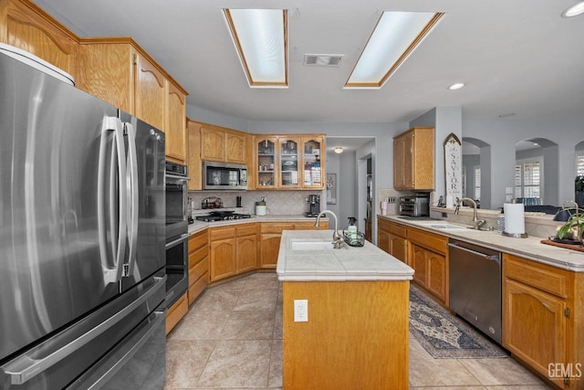 8628 Sandpines Dr, Bakersfield, CA 93312 - kitchen featuring stainless steel appliances, a sink, a center island with sink, arched walkways, and backsplash
