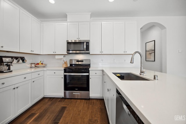 3116 Seymour St, Tulare, CA 93274 - kitchen featuring appliances with stainless steel finishes, a sink, arched walkways, dark wood-style flooring, and white cabinets