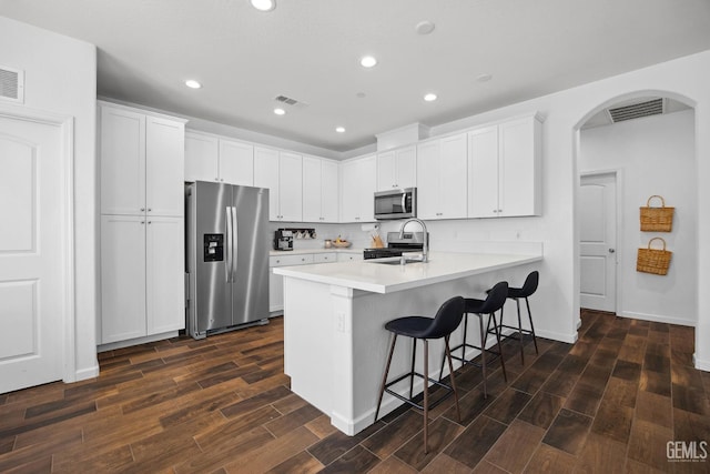 3116 Seymour St, Tulare, CA 93274 - kitchen featuring appliances with stainless steel finishes, a peninsula, dark wood-type flooring, a breakfast bar, and arched walkways