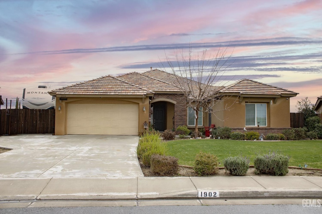 ranch-style house with a garage and a yard