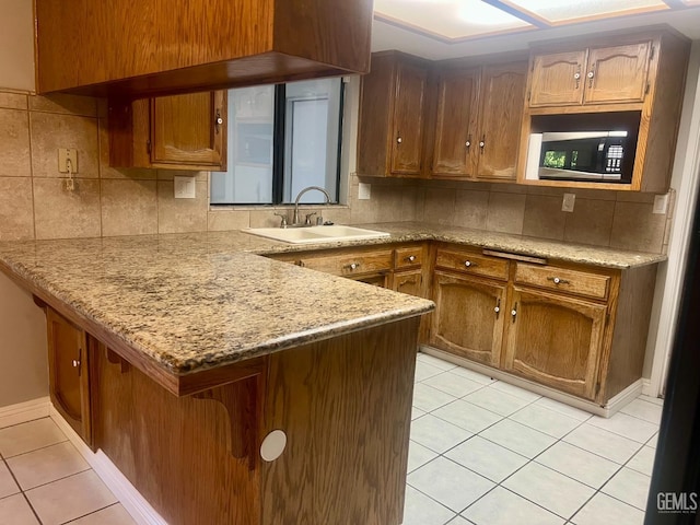 1325 Bayne Ct, Bakersfield, CA 93307 - kitchen with stainless steel microwave, light tile patterned floors, a peninsula, and tasteful backsplash