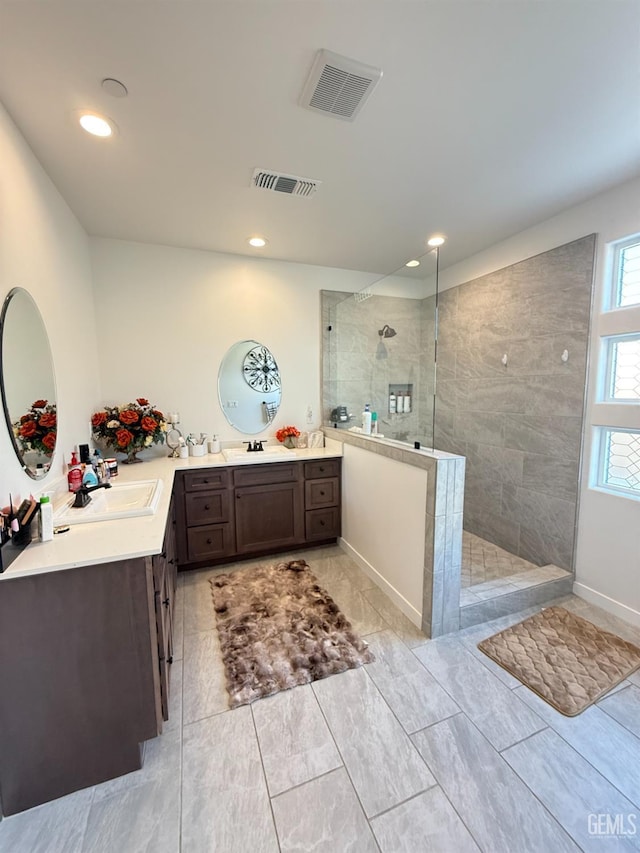 bathroom with a tile shower and vanity