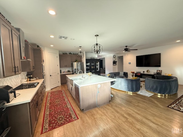 kitchen with tasteful backsplash, a kitchen island with sink, pendant lighting, and stainless steel appliances