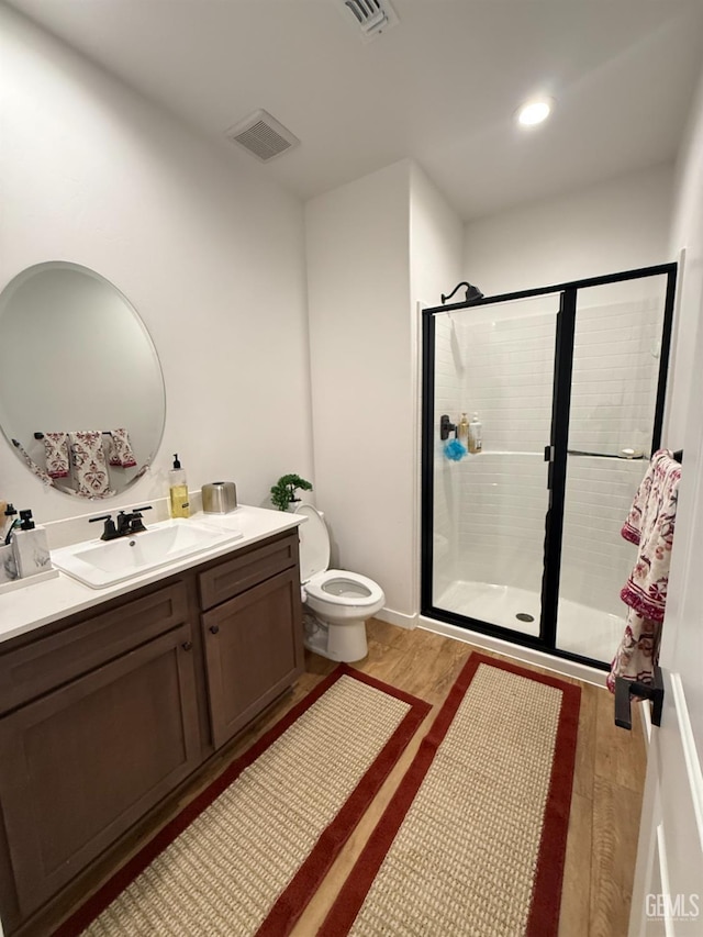 bathroom featuring vanity, toilet, wood-type flooring, and walk in shower