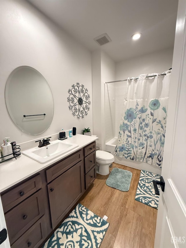 full bathroom with hardwood / wood-style floors, vanity, shower / bath combo, and toilet