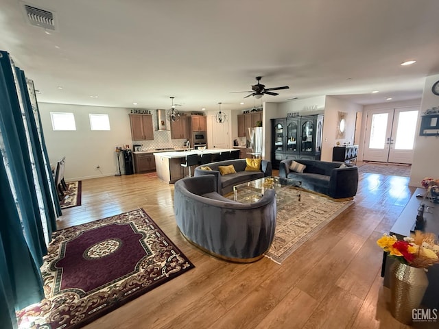 living room featuring french doors, light hardwood / wood-style flooring, and ceiling fan