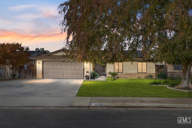 view of property hidden behind natural elements featuring a lawn and a garage