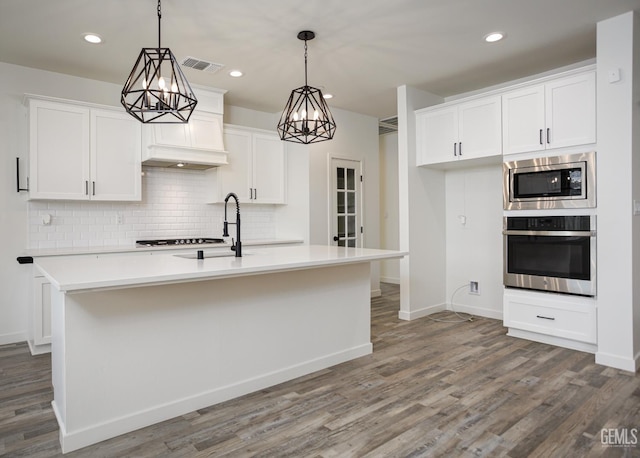 kitchen with stainless steel appliances, backsplash, white cabinetry, wood finished floors, and recessed lighting