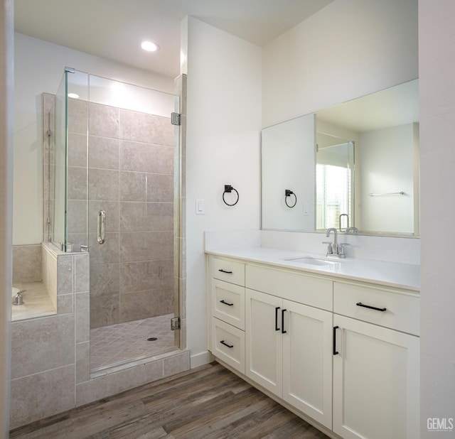 full bathroom with a stall shower, vanity, wood finished floors, a garden tub, and recessed lighting