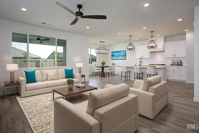 living area featuring recessed lighting, ceiling fan, wood finished floors, and a chandelier