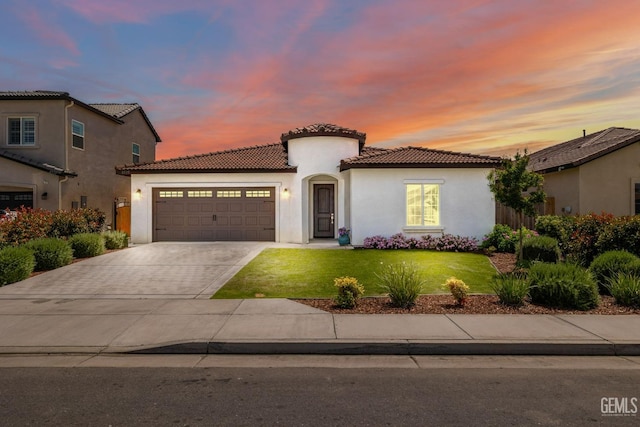 mediterranean / spanish-style home with an attached garage, a tile roof, a front lawn, and stucco siding