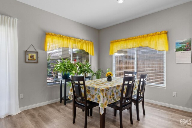 dining area with baseboards, light wood finished floors, and recessed lighting