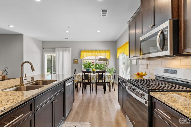 kitchen featuring dark brown cabinets, a healthy amount of sunlight, stainless steel appliances, and a sink