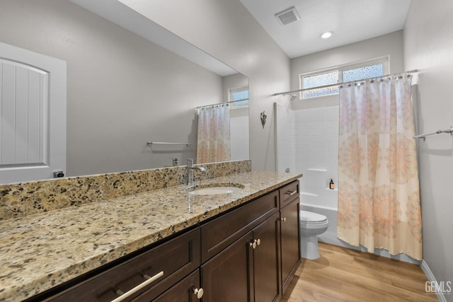 bathroom featuring wood finished floors, vanity, shower / tub combo with curtain, toilet, and visible vents