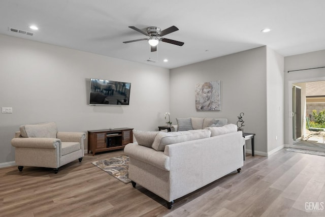 living room featuring a ceiling fan, light wood-style floors, and visible vents